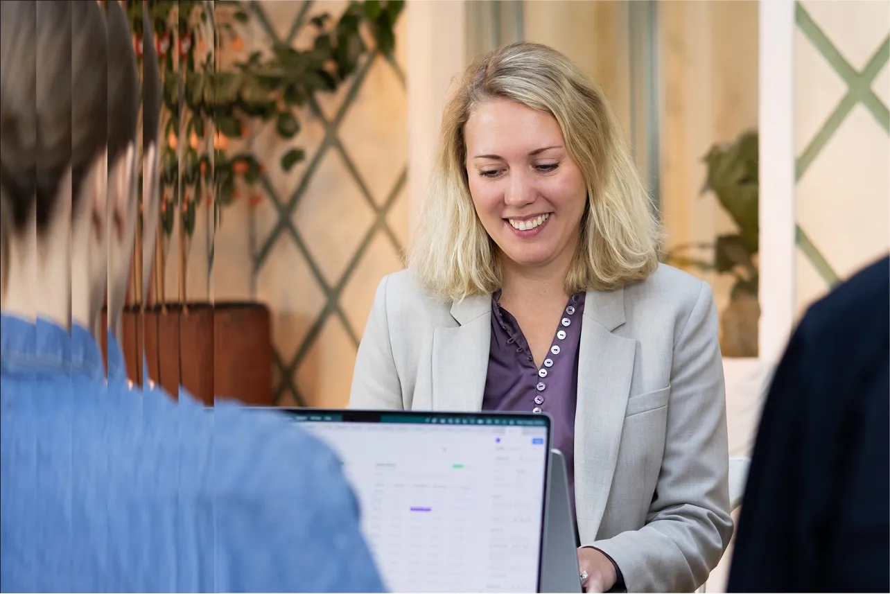 Two colleagues at a laptop in the Stockholm office, seen past a fluted glass wall